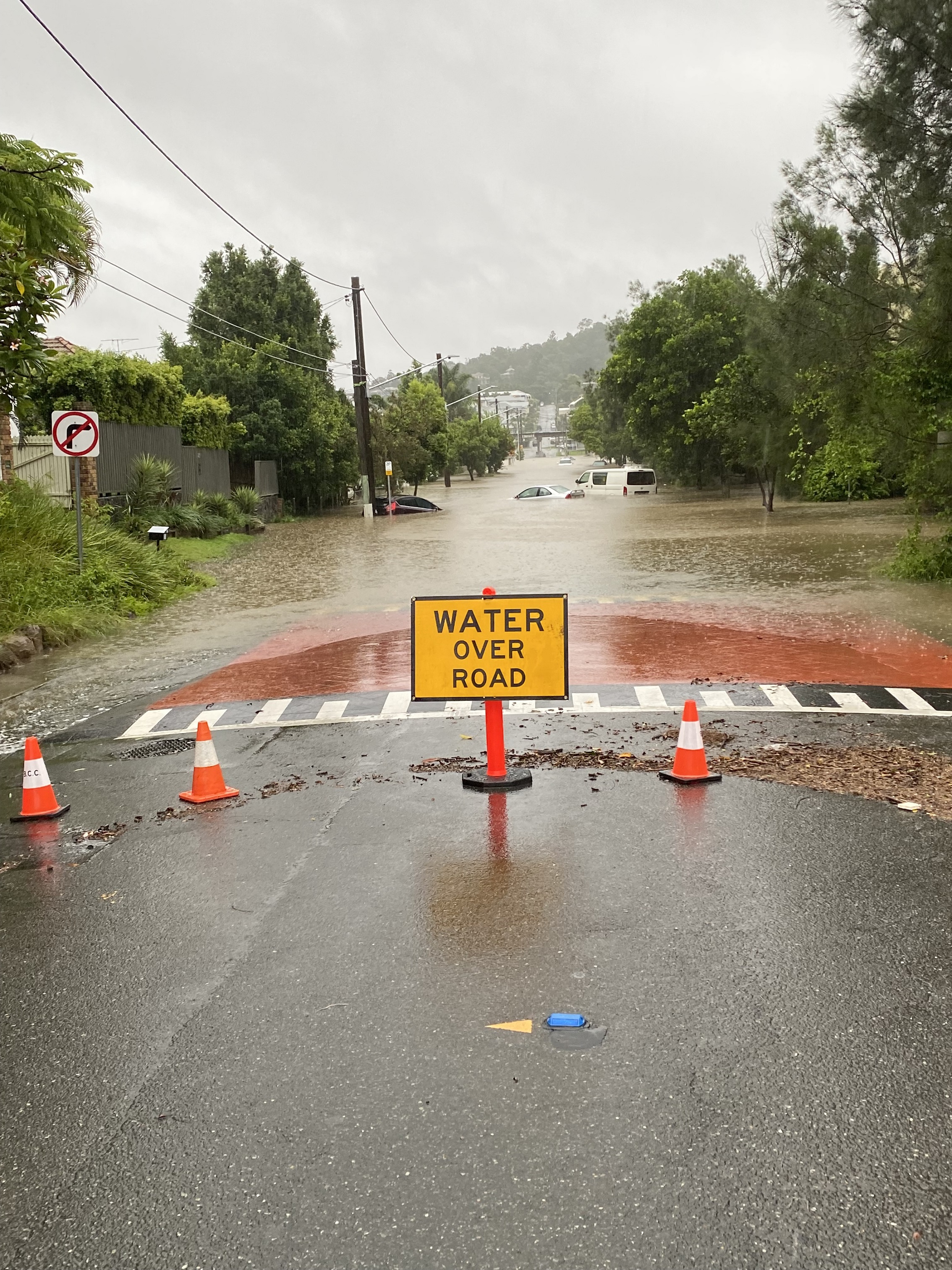 布里斯班街后面的洪水道路上的洪水警告标志，汽车在水中在恶劣天气事件中